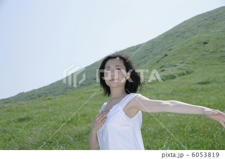 草原で腕を広げて立つ若い女性 6053819