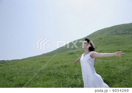 草原で腕を広げて立つ若い女性 6054269