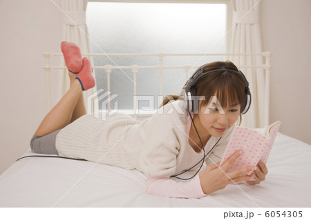 ヘッドフォンをしながら本を読む女性 6054305