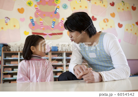 女の子とにらめっこをする幼稚園教諭 6054542