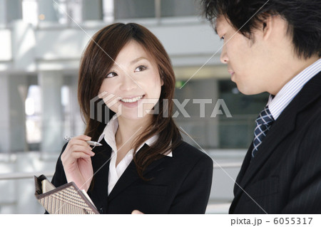 手帳を見ながら会話をする男性と女性 6055317