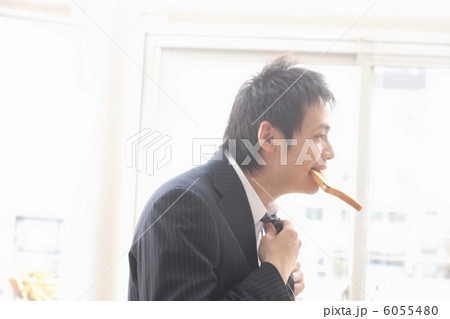パンを食べながら身仕度する男性 6055480