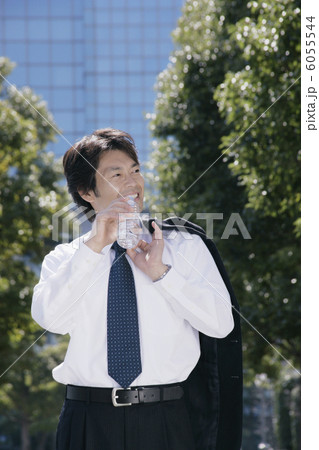 スーツの上着を肩に掛けて水を飲む男性 スーツの上着を肩に掛けて水を飲む男性 6055544
