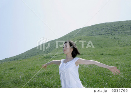 草原で腕を広げて立つ若い女性 6055766