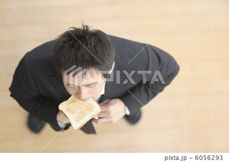 パンを食べながら身仕度する男性 6056293