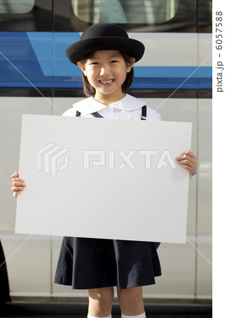 バスの前でホワイトボードを持った幼稚園の女の子 6057588