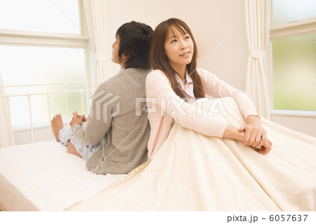 背中あわせに座るパジャマ姿の男女の写真素材