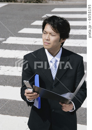 携帯電話と書類を持つスーツ姿の男性 6058195