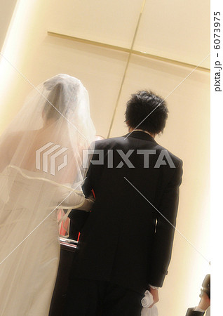 結婚式に腕を組んで登場する、タキシード姿の新郎と純白のウエディングドレス姿の新婦の写真 結婚式に腕を組んで登場する、タキシード姿の新郎と純白のウエディングドレス姿の新婦の写真 6073975