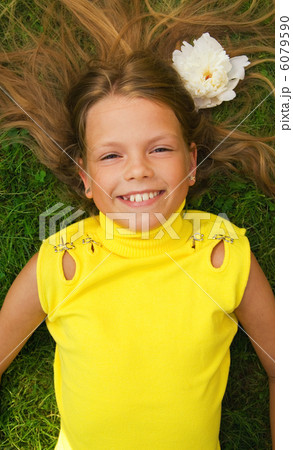 Happy young girl lying on a green grass 6079590