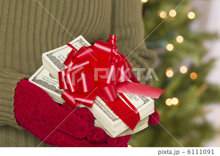 Woman Wearing Mittens Holding Stacks of Money with Red Ribbon 6111091