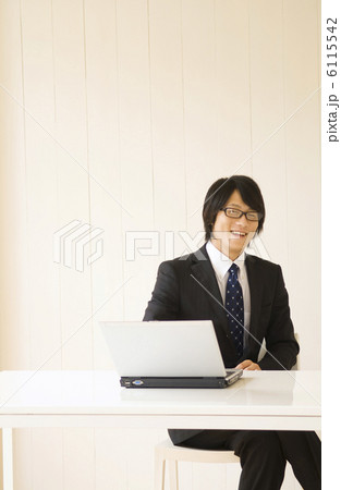足を組んでいる笑顔のビジネスマン 足を組んでいる笑顔のビジネスマン 6115542