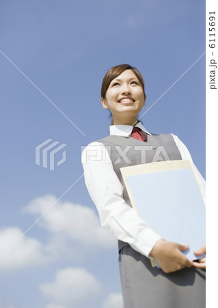 書類を持って遠くを見ている制服姿のOL 6115691