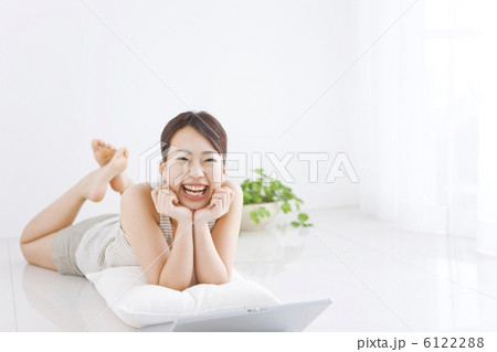 うつ伏せでくつろぐ笑顔の女性 6122288