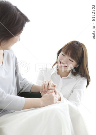 車イス乗ったシニア女性の手を握る若い女性 6122502