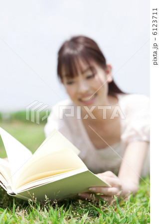 芝生に寝転んで本を読んでいる女性 芝生に寝転んで本を読んでいる女性 6123711