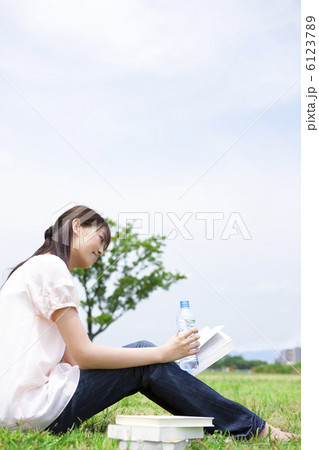 芝生に座って本を読んでいる女性 6123789