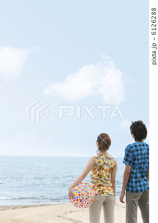 海辺に立って空を見上げているカップルの後姿の写真素材
