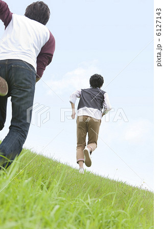 草原を走る男性2人の後姿の写真素材