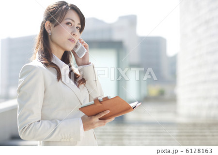 手帳を広げて携帯電話を持つビジネスウーマン 6128163