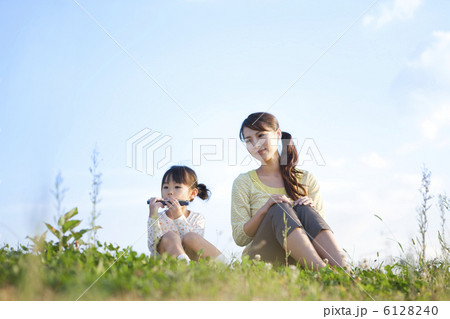 芝生に座ってハーモニカを吹く女の子と母親 芝生に座ってハーモニカを吹く女の子と母親 6128240