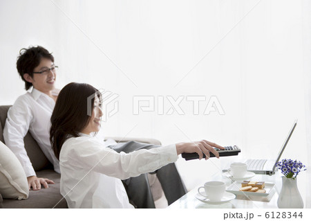 リモコンを操作する女性とソファーに座っている男性 6128344