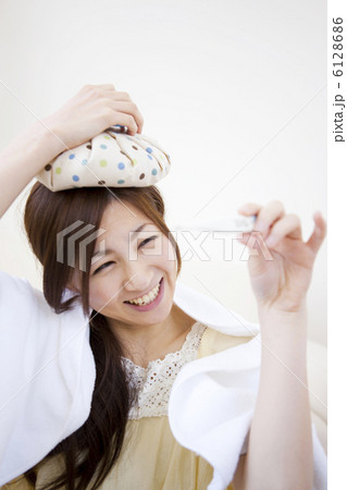 頭を冷やして体温計を見て笑顔の女性 頭を冷やして体温計を見て笑顔の女性 6128686