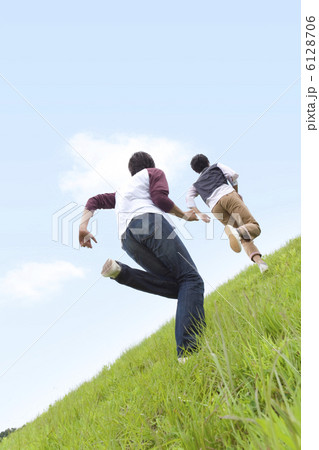 草原を走る男性2人の後姿の写真素材