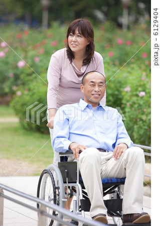 車いすに乗った夫と散歩をする妻 6129404