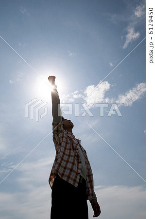 青空の下で拳を突き上げる男性の写真素材