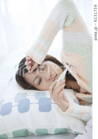 ベッドに横たわって体温計を見ている女性 ベッドに横たわって体温計を見ている女性 6131759