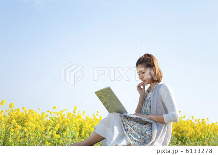 花畑に座ってパソコンをする女性 6133278