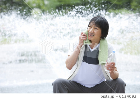噴水の前で汗を拭く中高年男性 噴水の前で汗を拭く中高年男性 6134092