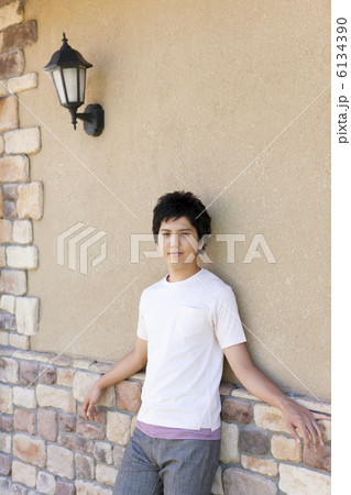 レンガの壁にもたれる若者男性 6134390