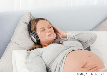 Pretty future mom listening to the music lying on a bed Pretty future mom listening to the music lying on a bed 6163573