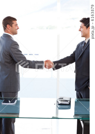 Cheerful businessmen closing a deal by shaking their hands 6163879