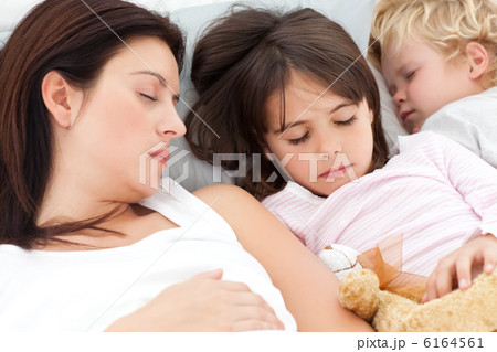 Adorable brother and sister sleeping with their mother in her be 6164561