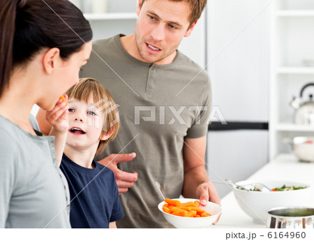 Little boy giving his mother a carrot while preparing lunch 6164960