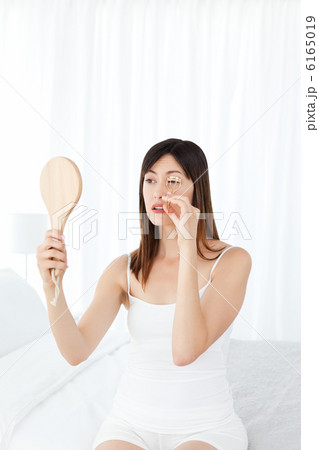 Woman curling her eyelashes Woman curling her eyelashes 6165019