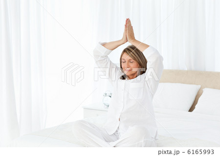 Senior practicing yoga on her bed Senior practicing yoga on her bed 6165993