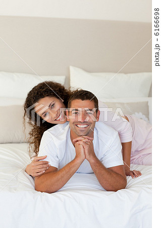 Pretty woman hugging her husband on their bed at home Pretty woman hugging her husband on their bed at home 6166698