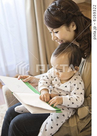 赤ちゃんに絵本を読み聞かせしている母親の写真素材