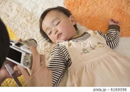 赤ちゃんの寝顔をデジタルカメラで撮影する父親の写真素材