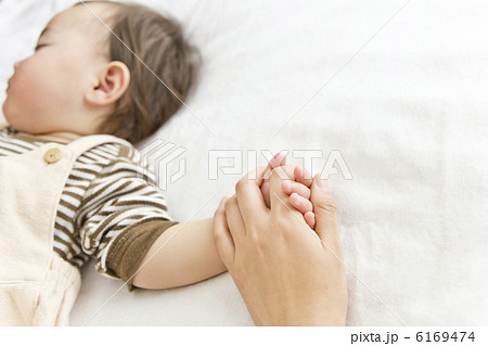 母親の手を握って寝ている赤ちゃんの写真素材