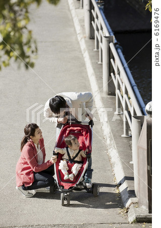 公園を散歩している赤ちゃんと若い両親 公園を散歩している赤ちゃんと若い両親 6169476