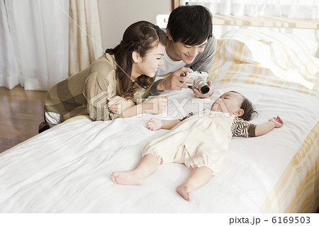 赤ちゃんの寝顔をデジタルカメラで撮影する両親 赤ちゃんの寝顔をデジタルカメラで撮影する両親 6169503