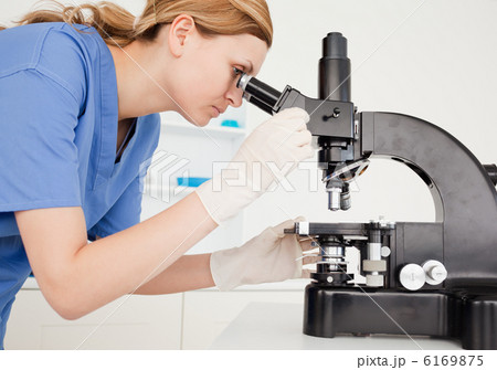 Female scientist conducting an experiment looking through a micr Female scientist conducting an experiment looking through a micr 6169875