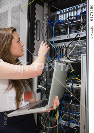 Woman adjusting server wires and holding laptop 6175266