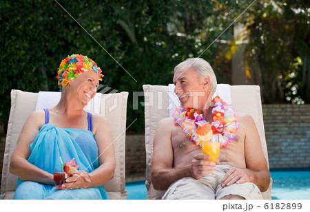 Mature couple drinking a cocktail  beside the swimming pool 6182899