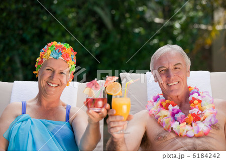 Mature couple drinking a cocktail beside the swimming pool Mature couple drinking a cocktail beside the swimming pool 6184242